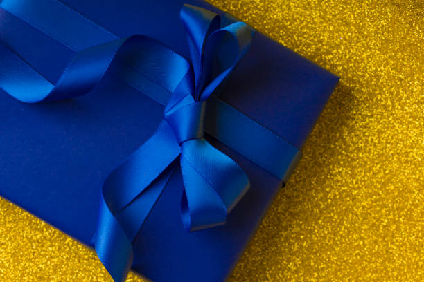 istock Gift Box In Blue Wrapping Paper On A Beautiful Abstract golden  Background. close up 1201092929
