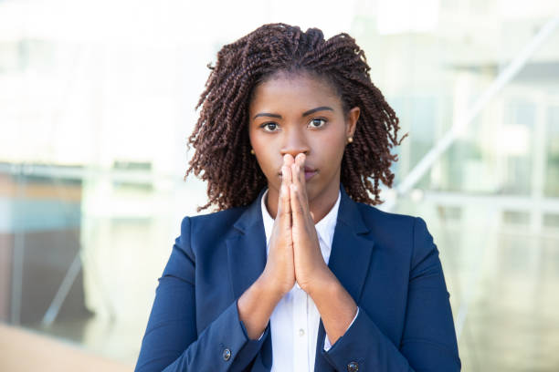 istock Young businesswoman praying and looking at camera 1201100787