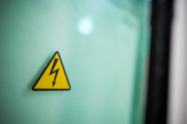 istock Sign danger high voltage. Sign dangerously high voltage electricity. A yellow triangle mark with a lightning bolt in the center. This warning is painted on an old metal surface painted with gray paint 1201111225