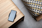 A mobile phone charging wirelessly is on a wooden table