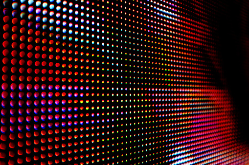 Angled close-up of liquid crystal display (LCD) sign, showing black and red pixels.