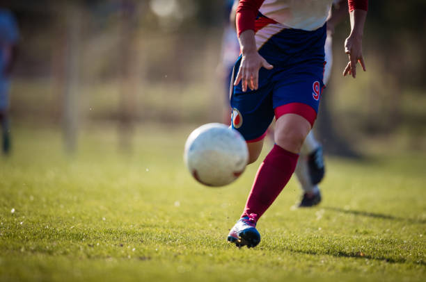 Unrecognizable female soccer player with a ball during a match on playing field. Copy space.
