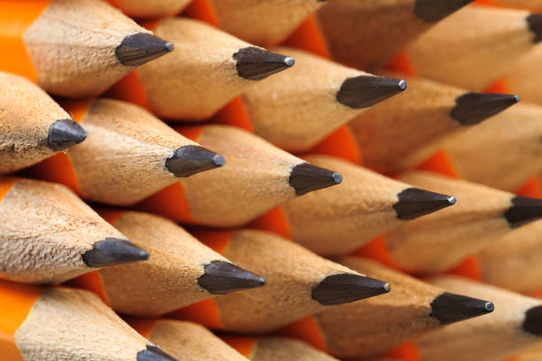 Top view of several black pencils located in row on wooden table. Sharp pens laying in chaotic order. Tool for drawings on paper. Equipment for art concept