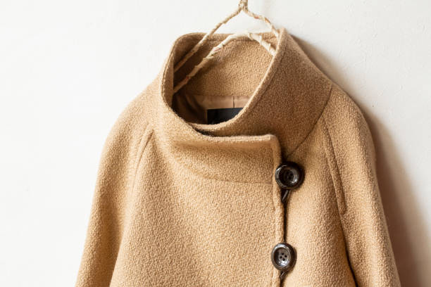 istock beige wool coat hanging on clothes hanger on white background. 1201122017