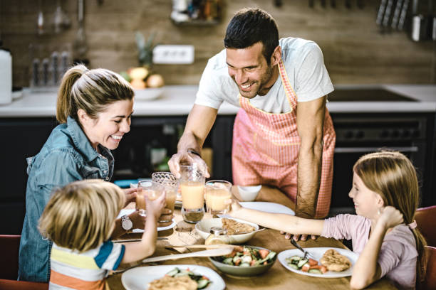 istock Young happy family toasting with juices at dining table. 1201122445