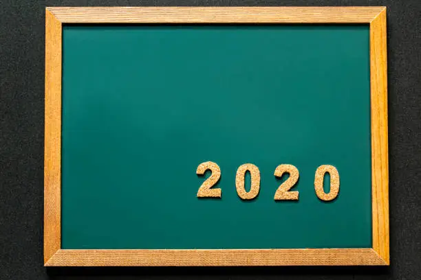 Photo of Set of 2020 of cork isolated on green blackboard and black color background and opy space.