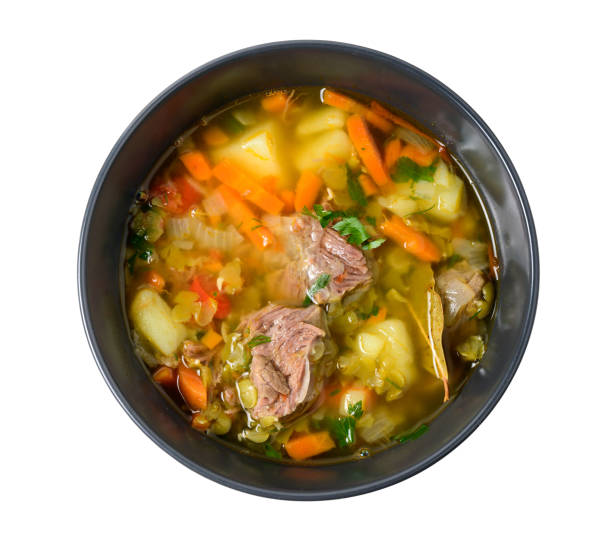istock Meat soup with vegetables in black bowl isolated on white. Top view 1201133381