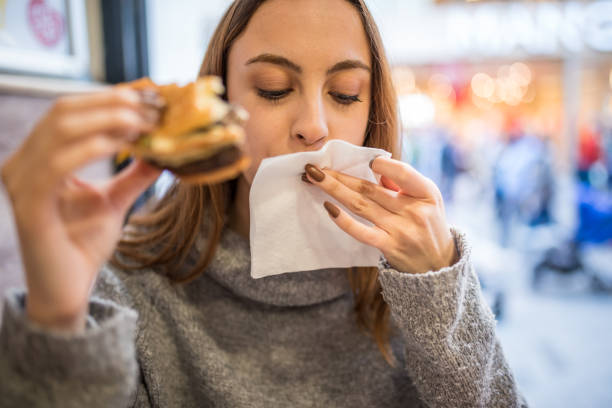 Beautiful young girl cleans her mouth after a big bite stock photo