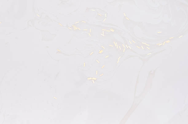 istock White liquid paint texture with stains, stripe and golden floating glitter on surface as modern abstract background. 1201138329