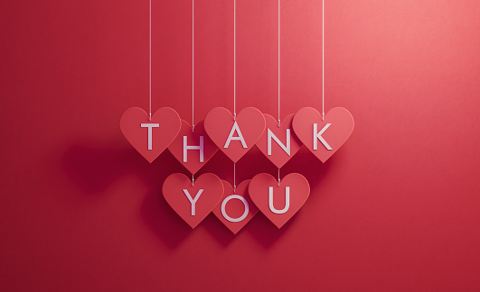 Thank you writes over red heart shapes hanging over red background, Horizontal composition. Thank you concept.