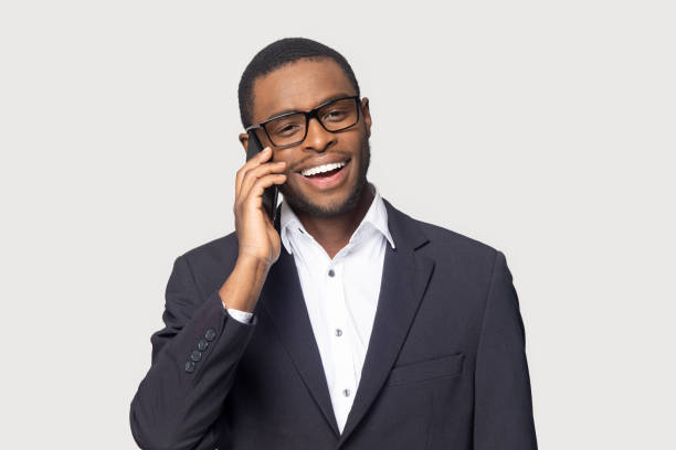 istock Smiling black businessman talk on cellphone isolated in studio 1201144318