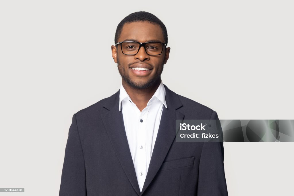 Smiling black man in suit posing on studio background Smiling african American millennial businessman in glasses isolated on grey studio background posing, satisfied successful black male in formal suit wearing spectacles look at camera laughing Headshot Stock Photo