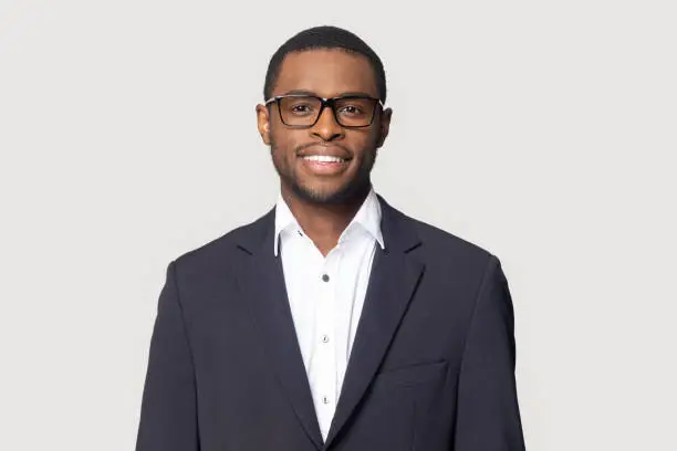 Photo of Smiling black man in suit posing on studio background