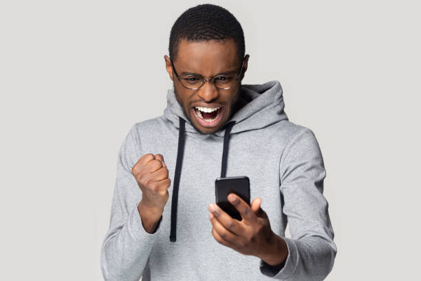 istock Excited black man hold smartphone scream wining online 1201144404