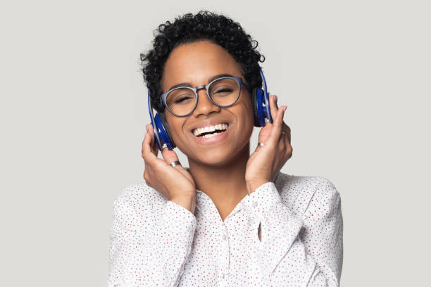 sorridente ragazza nera in cuffie bluetooth godere di musica - music women disco joy foto e immagini stock