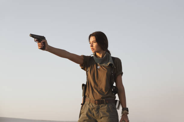 mulher em pé com uma arma ao ar livre no deserto - gun women handgun armed forces - fotografias e filmes do acervo