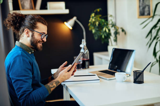 istock Young smiling attractive caucasian bearded graphic designer sitting at office  and using tablet. 1201151733