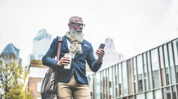 istock Senior business man using smartphone app walking to work - Entrepreneur drinking coffee while going to office - Job, business, elegant, fashion and confident concept - Focus on face 1201154641