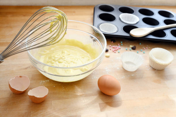 istock whisk with cupcake dough, egg shells and a muffin tin on a wooden kitchen board, baking concept 1201154977