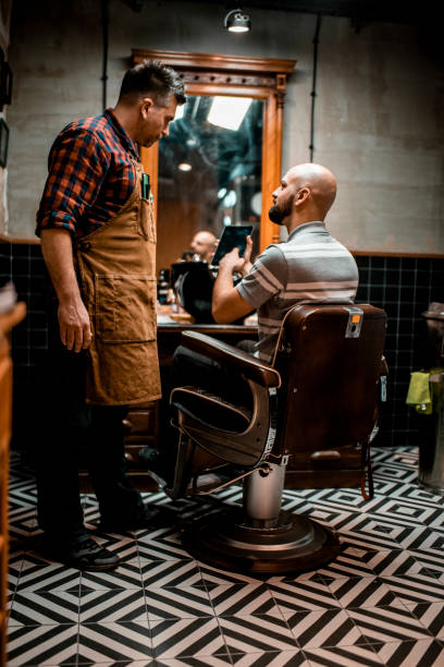 istock Customer showing the barber something on a digital tablet while sitting in a barber chair 1201157085
