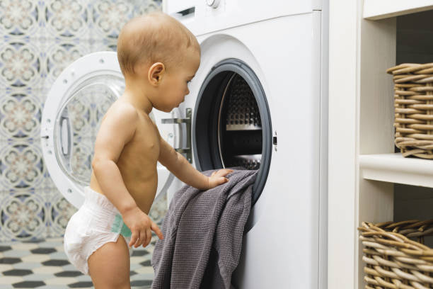 istock Cute baby boy is looking inside the washing machine 1201157765