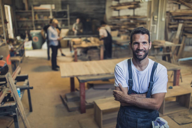 istock Happy manual worker with crossed arms in carpentry workshop. 1201159996