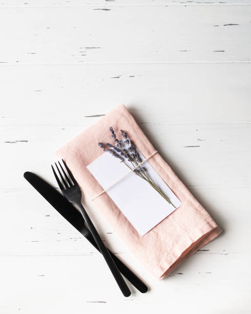 istock Rustic romantic table setting with paper card, pink napkin, lavender and appliances on white wood table. Top view. Copy space 1201160338