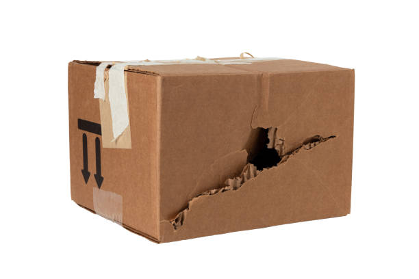 torn hole in the wall of a cardboard post box Damaged crumpled postal cardboard box with a punched side and a black big hole. poor delivery of goods cargo container container open shipping stock pictures, royalty-free photos & images