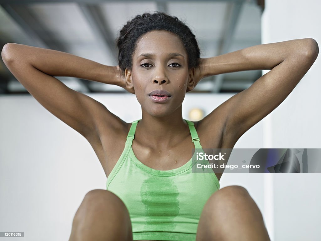 african woman doing series of crunch in gym young african american woman in green sportswear exercising abdominals in fitness club, looking at camera. Horizontal shape, front view, waist up Sit-ups Stock Photo