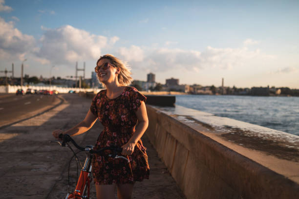 istock Happy woman pulling her bicycle next to sea in Habana 1201164770