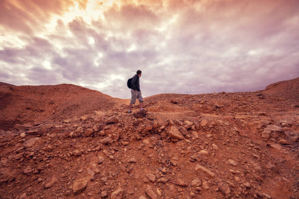istock Human hiking in a desert. Desert landscape with dramatic cloudy sky 1201166074