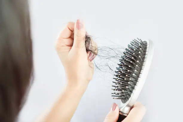 Photo of Asian woman hand holding hair loss falling on comb