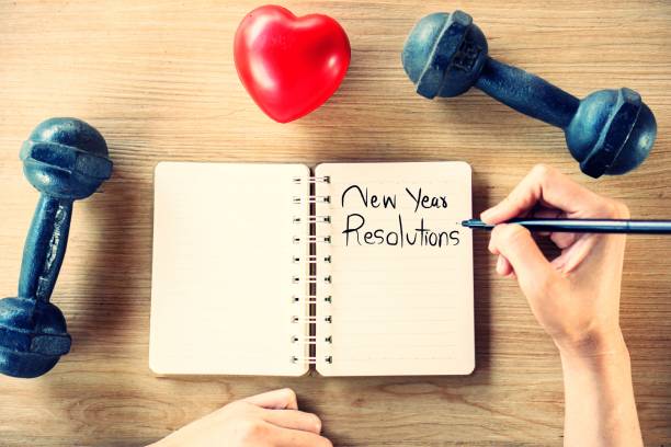 istock hand writing text new year resolutions on notebook for sport concept with dumbbell, heart shape on table 1201166257