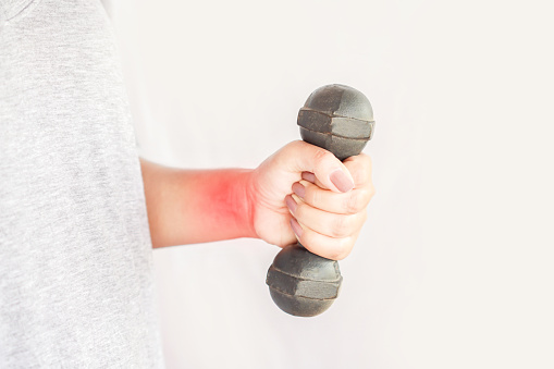 closeup woman hand holding dumbbell suffering from wrist and arm pain ,sport injury concept