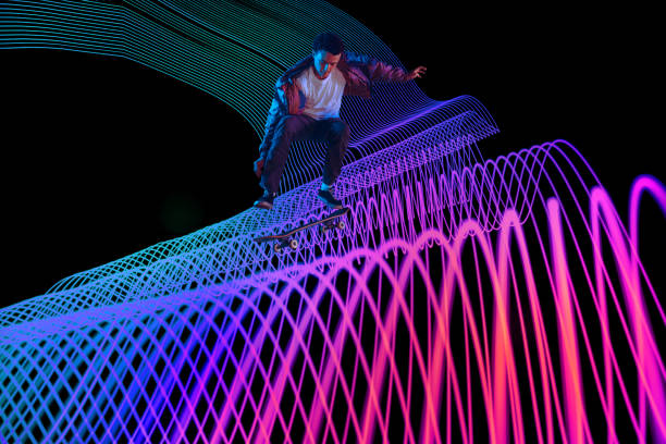 istock Caucasian young skateboarder riding on dark neon lighted line background 1201170452