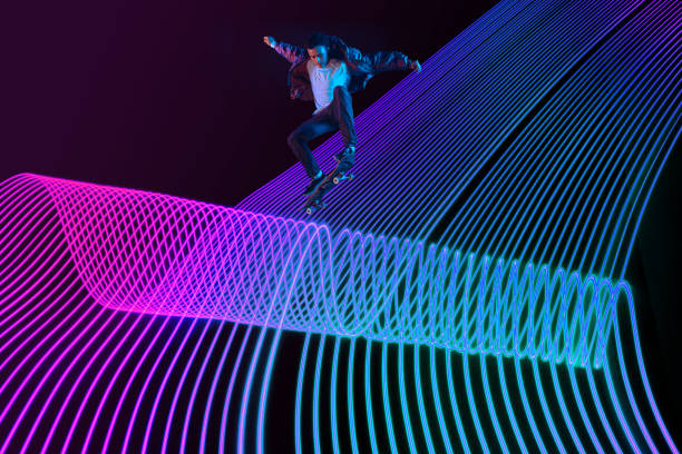 istock Caucasian young skateboarder riding on dark neon lighted line background 1201170537