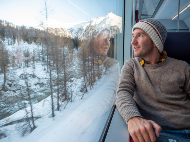 junger mann tourist mit zug in der schweiz mit blick durch fenster - tourism panoramas winter travel locations stock-fotos und bilder