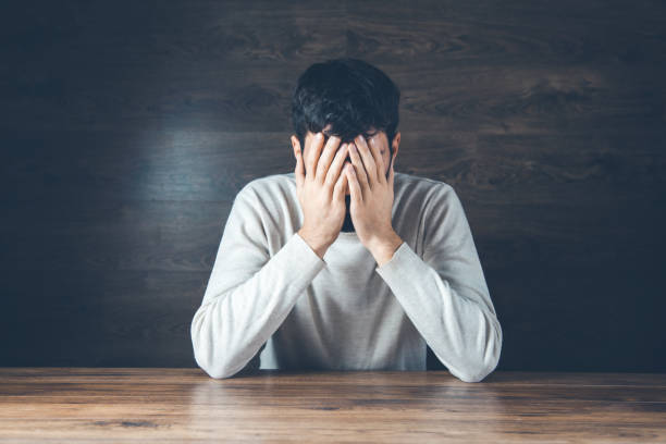 istock sad man hand on head on dark background 1201172818