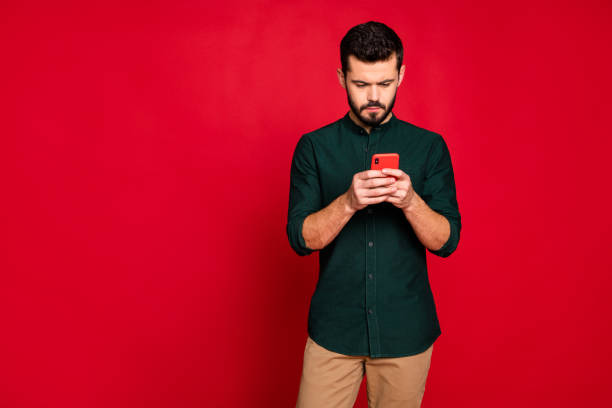 istock Portrait of concentrated guy use his smartphone solve work problems on social network wear casual style brown pants trousers isolated over red color background 1201173394