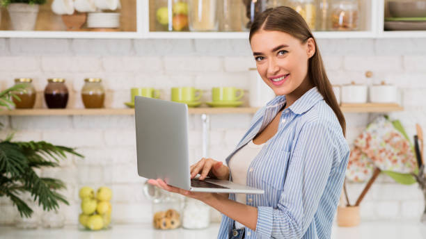istock Searching for recipe. Girl using laptop in the kitchen 1201174708