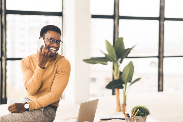 istock Black guy talking on phone sitting on the table 1201174891