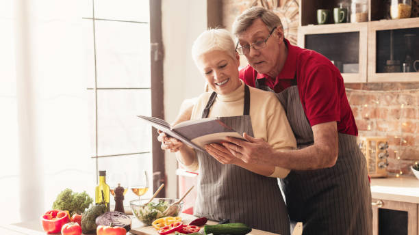 istock Senior couple reading recipes at kitchen interior, panorama 1201175242