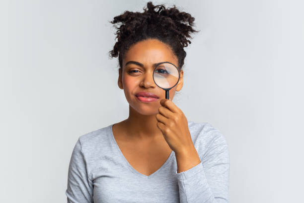 istock Suspicious young woman looking at camera through magnifier 1201176010