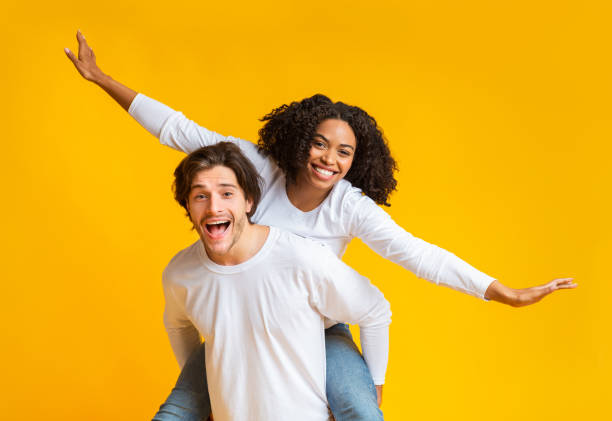 istock Joyful multiracial couple having fun together over yellow background 1201177003