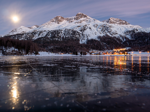 Frozen lake and snowcapped mountain in Switzerland, reflection on lake surface