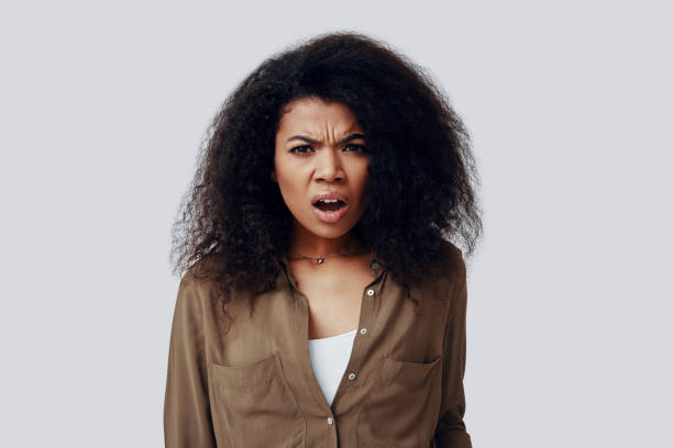 istock Confused young African woman looking at camera and making a face while standing against grey background 1201180825