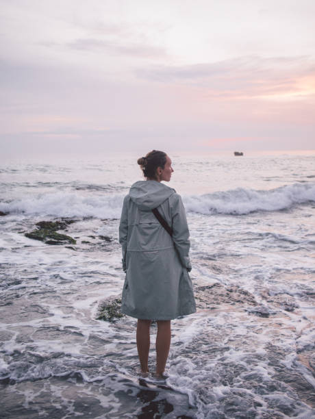 Young woman standing in water at beach stock photo