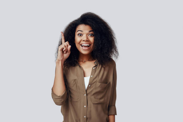 istock Beautiful young African woman smiling and looking at camera while standing against grey background 1201181471
