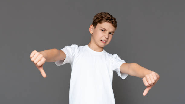istock Displeased teen boy gesturing thumbs down with both hands 1201183679