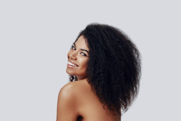 istock Carefree young African woman smiling and looking at camera while standing against grey background 1201184477